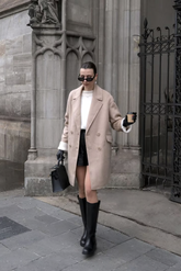 a lady in a white sweater, a pair of black shorts and a long alpaca wool coat